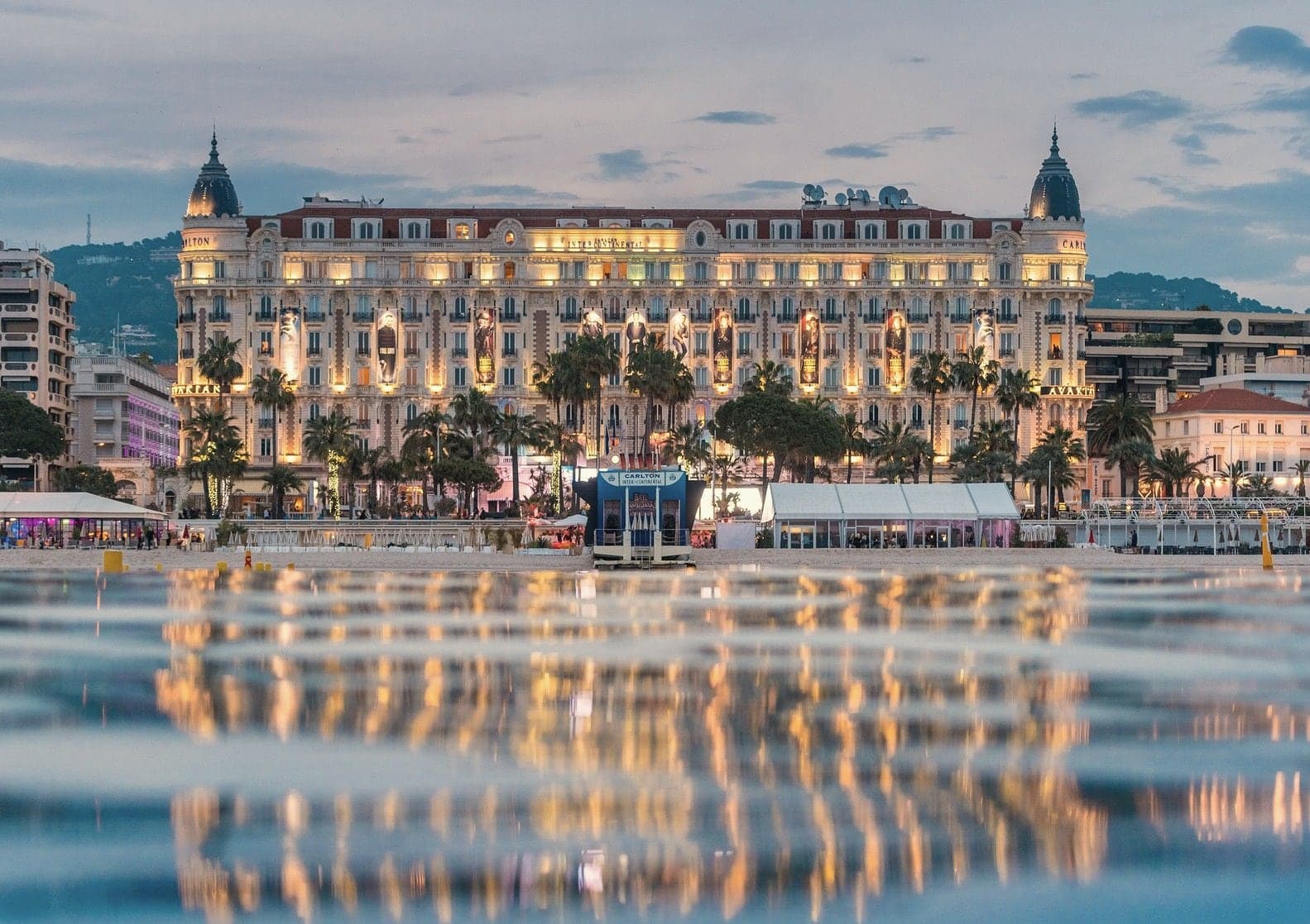 The Carlton hotel on the Croisette in Cannes at dusk, reflected in the sea
