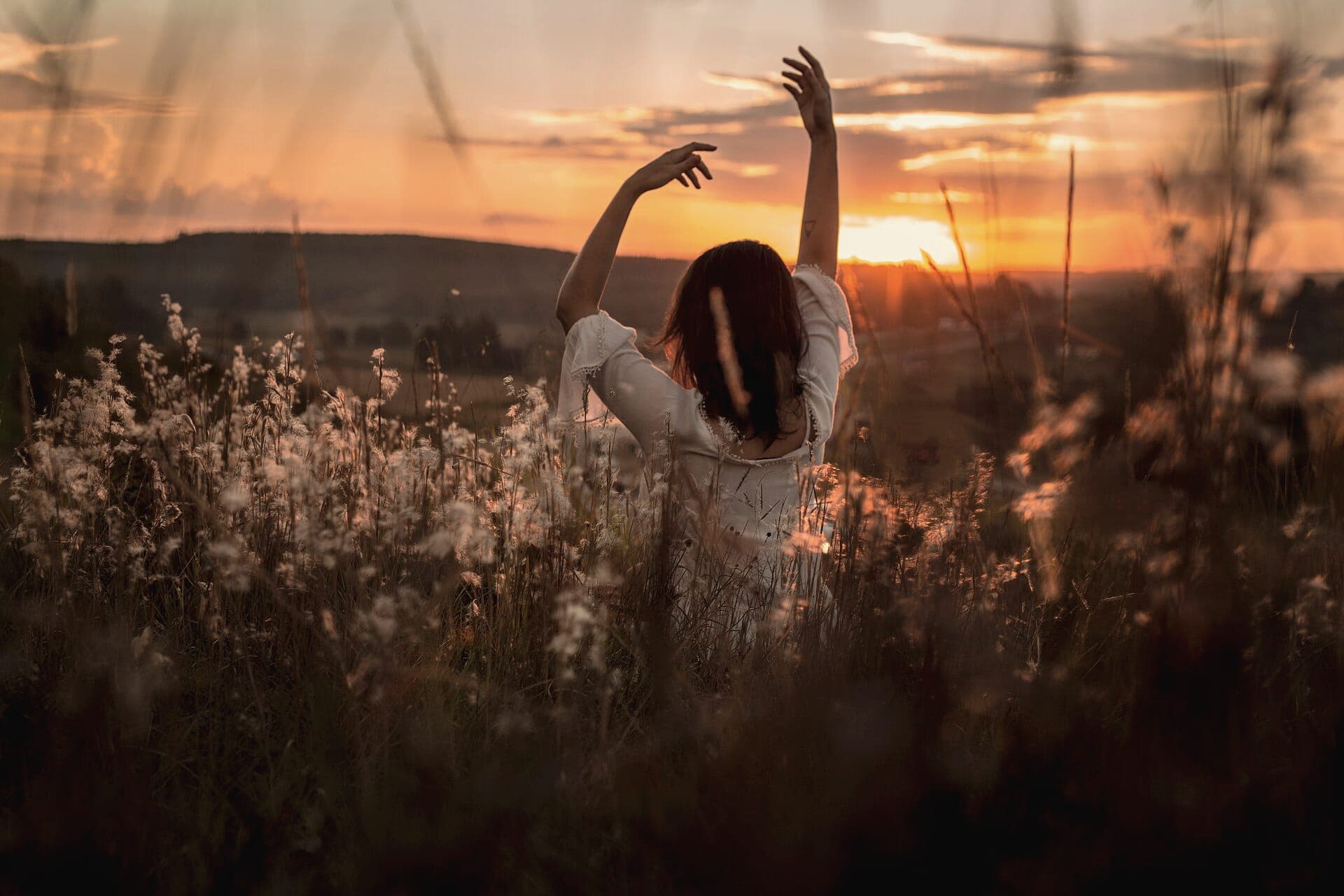 A woman stretching in tall grass in golden evening light
